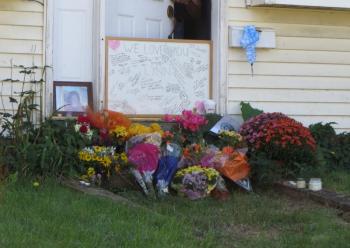 A whiteboard is full of messages about Lynn Marie (Day) Arsenault at the site of the shooting, at her home on Waldo Avenue, along with flowers and a picture. (Photo by Erica Thoms)