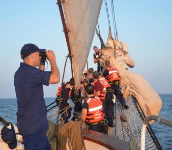 On the Eagle bowsprit, a crew furls the jibs while the southwestern horizon is scanned. (Photo by Lynda Clancy)