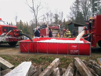 Firefighters dump water from a tanker truck into a portable pool allowing the truck to get more water. The bubbles are fire suppressant that a firefighter on the scene said is similar in composition to dish soap. (Photo by Ethan Andrews