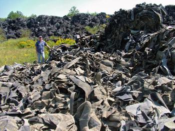 Maine Department of Environmental Protection Project Manager Michael Parker stands amid a portion of the 27,000 tons of carpet-like material on the site of an abandoned shooting range in Warren. This week, the agency awarded the material to Massachusetts-based company that plans to turn it into composite lumber. (Photo by Ethan Andrews)