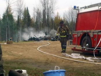 A firefighter works at the scene of an outbuilding that burned to the ground Thursday morning in Stockton Springs. (Photo by Ethan Andrews)