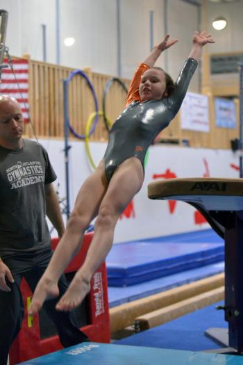 Lauren Schenk dismounts from the vault as coach Jonas Contakos spots. (Photo by Ron Hawkes)
