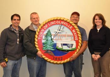 Walter Simmons carved and painted a beautiful new town seal that will hang at the town office in the assembly room. Steve Marin, David Kinney, Mike Paris and Amanda Austin.