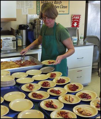 Jane Bennett dishes up dessert in the kitchen. (Photo by Chris Wolf)