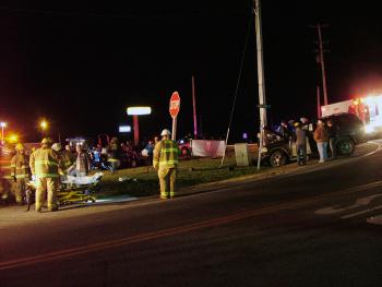 A view of the scene, looking across Route 220 (Knox Ridge South) from just south of the intersection with Route 137. The Ford SUV is visible at right. At left, emergency workers help one of the occupants of the vehicle onto a stretcher. (Photo by Ethan Andrews)