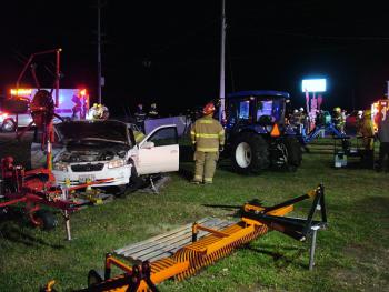 Emergency workers prepare to remove the driver from a car, left, that reportedly ran a stop sign at the intersection of Routes 137 and 220 in Knox and hit a westbound SUV. The SUV hit the utility pole visible in the background, while car came to rest amid farm equipment displayed outside Ingraham Equipment. (Photo by Ethan Andrews)