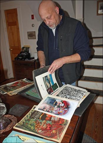 Ben McGinnis thumbs through his illustration portfolio in the kitchen of his home in Hope. (Photo by Holly S. Edwards)