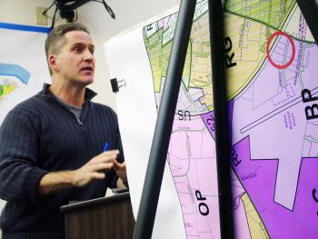 George Delaney, president of Maine Maritime Products, tries to persuade the City Council on Tuesday to allow him to serve takeout meals at MMP’s seafood processing facility in the Belfast Business Park. The circle on the map in the foreground marks the location of the business. (Photo by Ethan Andrews)