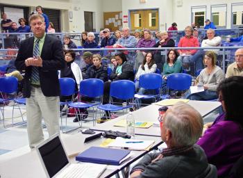 Superintendent Brian Carpenter, standing, fields a question from Belfast director Charles Grey during a school board meeting last month in Searsport at which residents voiced concerns over proposed consolidation plans. On Tuesday, the board voted to abandon the plans altogether. (Photo by Ethan Andrews)