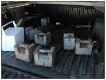 The bed of Wiggin’s pickup truck carries the bulk of the 450 pounds worth of assorted weights he uses to test local scales. Each of these weighs 50 pounds. (Photo by Ethan Andrews)