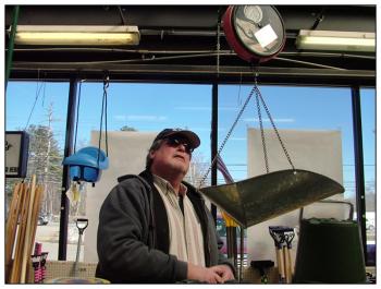 Wiggin checks the reading on a hanging scale at Aubuchon Hardware in Belfast. (Photo by Ethan Andrews)