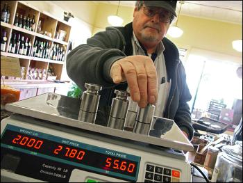 Robert Wiggin, sealer of weights and measures for 25 Midcoast municipalities, checks the accuracy of a scale at Eat More Cheese in Belfast. (Photo by Ethan Andrews)