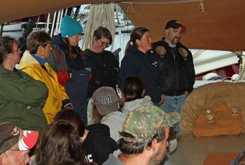 Crew of schooner Mary Day and Appleton Village School parents and students keep dry under the canopy Tuesday night. (Photo by Holly S. Edwards)