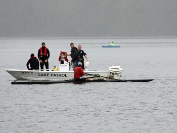 The man in the sculling boat, Jeff Foltz of Camden, who was rowing with his friend, Jim Wescott, who fell out of his own boat and went missing on Lake Megunticook Tuesday morning after 8 a.m. talks to Camden firefighters before rescue swimmers enter the water to try and find the missing man. (Photo by Holly S. Edwards)