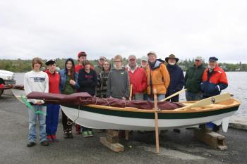 Searsport District High School sophomores stand with lead instructor Greg Rossel, far right, and other volunteers behind one of the two dinghies they created. (Photo by Erica Thoms)