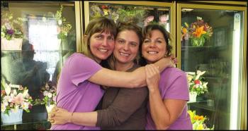 Krista Tolman, Gretchen Richards and Lisa Farley have a group hug in front of a cooler of flowers at Hoboken Gardens. (Photos by Chris Wolf)