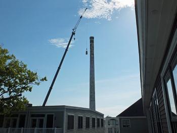 A Cote Corp. crane lifts a basket to the top of the 180-foot-tall Knox Mill smokestack Tuesday morning. (Photo by Holly S. Edwards)