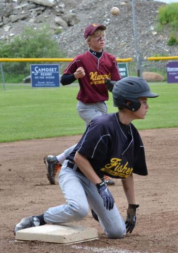 A Fisher player, front, gets up from sliding into third base, while a Kiwanis player, back, works on keeping the ball from going into the outfield. (Photo by George Harvey)
