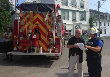 Knox County Sheriff’s Detective Dwight Burtis, left, shows the photo of the suspected incendiary device to an unidentified member of the Maine Fire Marshal’s Office. (Photo by Lynda Clancy)
