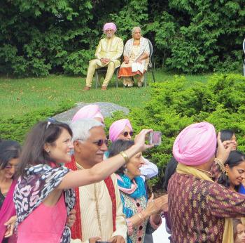 Grandparents of the bride wait in Goodridge Park for the groom and his family to arrive, while wedding guests record the processional coming their way. (Photo by Richard Anderson)