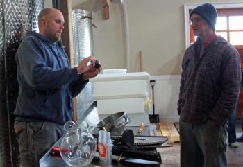 Breakwater Vineyards Property Manager Jake Oliver, left, explains how a refractometer is used to measure the sugar level in either wines or mead they make onsite. (Photo by Holly S. Edwards)