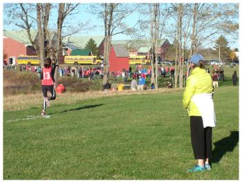 A coach watches a runner head into the final stretch. (Photo by Ethan Andrews)