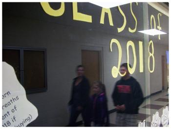 Visitors to Belfast Area High School reflected in a display case. (Photo by Ethan Andrews)