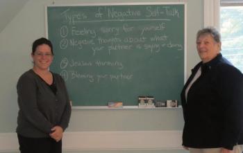 Amber Wotton and Ellie Hutchinson stand in the Time for Change classroom in Rockland with a blackboard used during the last session. (photo by Erica Thoms)
