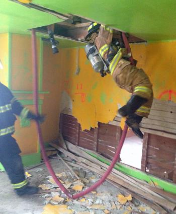 This shows a firefighter (not Billy Smith) making their way through a hole in a ceiling to the floor below using a charged line (hose) to slide down. It’s part of the Rochester Drill, which was included in last week’s multi-town RIT training in Rockport and Searsmont. (Courtesy Jason Peasley)