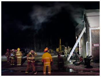 The view from Swan Lake Avenue, as firefighters continue to work on the upper floor of the contractor’s workshop building in Monroe Village. (Photo by Ethan Andrews)