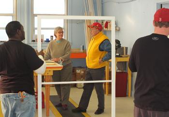 Workers add foam around the window insert and check for quality control before signing off on a finished product.