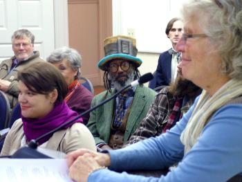 Poet and musician Toussaint St. Negritude, center, at Belfast City Hall, Dec. 16, where he was appointed to be the city’s next poet laueate. Former laureate Linda Buckmaster, foreground, announces the recommendations of a search committee. St. Negritude was joined by current poet laureate Ellen Sander, sitting to his right, and her predecessor in the honorary post, Jacob Fricke, back right. (Photo by Ethan Andrews)