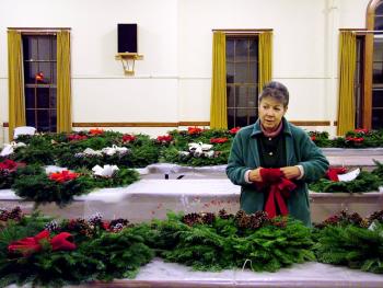 Dawn Voigt attaches one of over 800 bows she’s hand tied to adorn wreaths sold by First Church in an annual fundraiser that dates back 84 years. (Photo by Ethan Andrews)