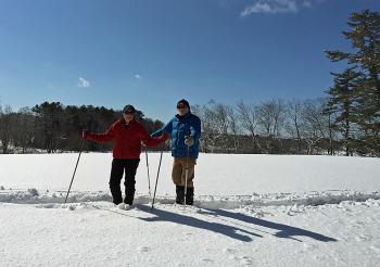 A pair of snowshoers, Jack and Barb Moore, make their way back across the Aldermere Farm cow pasture, having trekked the Lily Pond trail. (Photo by Holly S. Edwards)