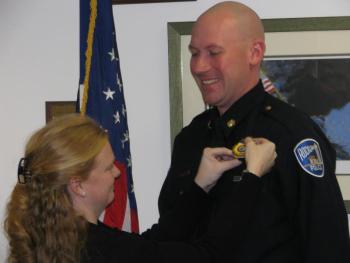 Bobbi Young pins a new badge onto her husband, Chris Young’s uniform Feb. 2, after his appointment as the new Rockland Police Deputy Chief. (Photo by Sarah Shepherd)