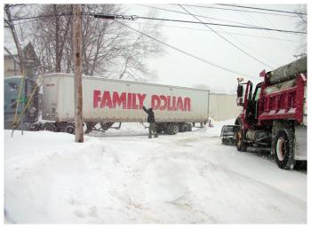 A city sand truck and neighbor Vic Tredwell converge on the scene as Evan Fletcher attempts to get his truck out of the loading area behind Family Dollar in Belfast, Feb. 2. (Photo by Ethan Andrews)