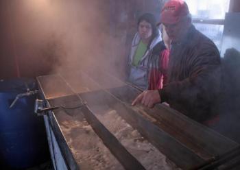 Skip Pound, right, explains the maple syrup extraction process to a visitor, Gabriella Blanco. (Photo by Holly S. Edwards)