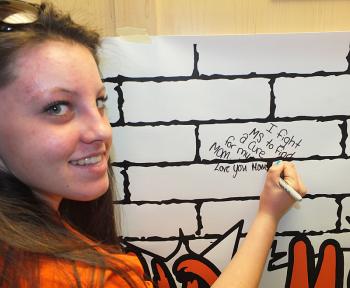 Jordon Mini, signing the MS wall in support of her mother. It reads, “I fight MS to find a cure for my mom.”