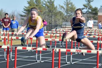 Medomak Valley’s Ashlee Wilson, battles a Boothbay runner in her first ever 100 meter hurdles. Wilson finished third in her heat here and fifth overall with a very impressive start to hurdles. (Photo by Ron Hawkes)