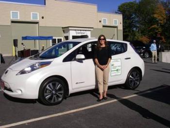 Jennifer Puser Brennan of the Greater Portland Council of Governments shows off the Nissan Leaf GPCOG leased through CMP’s PEV grant program.