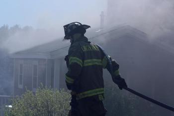 Wind Thursday afternoon kept moving the smoke around while firefighters worked to put out the flames inside the home. (Photo by Holly S. Edwards)
