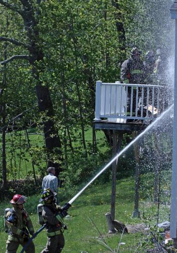 Firefighters work on the fire at the back of the residence, where and outside wall and the kitchen inside were most damaged Thursday afternoon. (Photo by Holly S. Edwards)