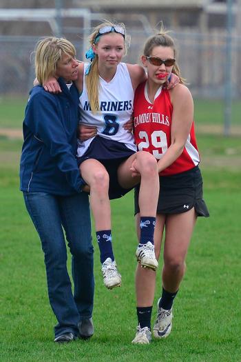The play of the game was Camden Hills Hannah Wincklhofer, right, helping to carry Oceanside’s Kelsey Brooks, center, off the field after an injury along with Oceanside coach Angie Vachon. (Photo by Ron Hawkes)