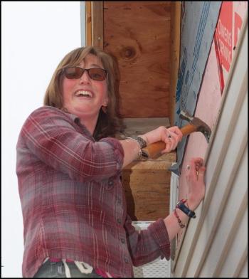 Hannah Tannebring works outside removing siding.