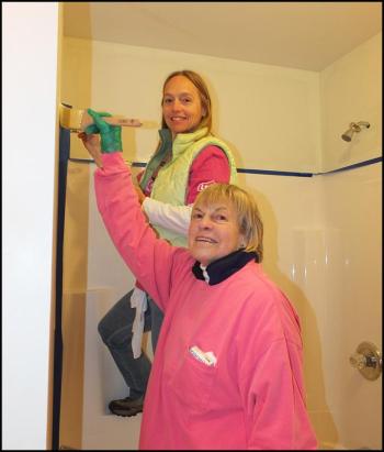 Kelli Sabatini and Susan Taylor apply a coat of paint in the bathroom.