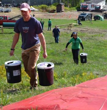 Eric Verite and Rachel McCormick haul water to the children’s slide. (Photo by Lynda Clancy)
