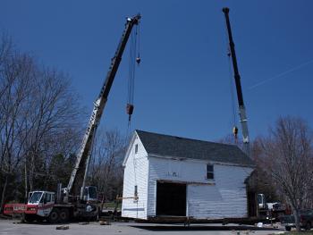 The barn behind 59 Elm St., a house owned by the First Congregational Church of Camden that has served as a residence for Coastal Opportunities tenants for 25 years, is lifted from its foundation Monday morning and moved next door to 63 Elm St., a parcel owned by Denise Pukas. (Photo by Holly S. Edwards)