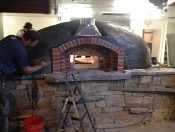 The wood-burning oven, made of granite and clay, is constructed by the community, and is a signature part of every Flatbread Company restaurant. (Photo courtesy Allen Mitchell)