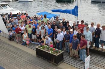 The crews of Wayfarer Marine and Lyman-Morse assemble behind the Lymans as they cut the symbolic ribbon of a new venture. (Photo by Lynda Clancy)