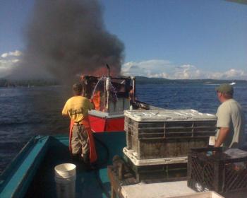 Lobstermen Jason St. Clair and Jay Osgood hose down the burning vessel. (Photo courtesy Richie Osgood)